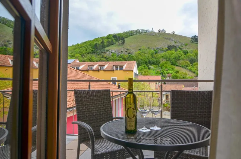 Balkon hotelového pokoje s lahví vína, výhled na Svatý kopeček